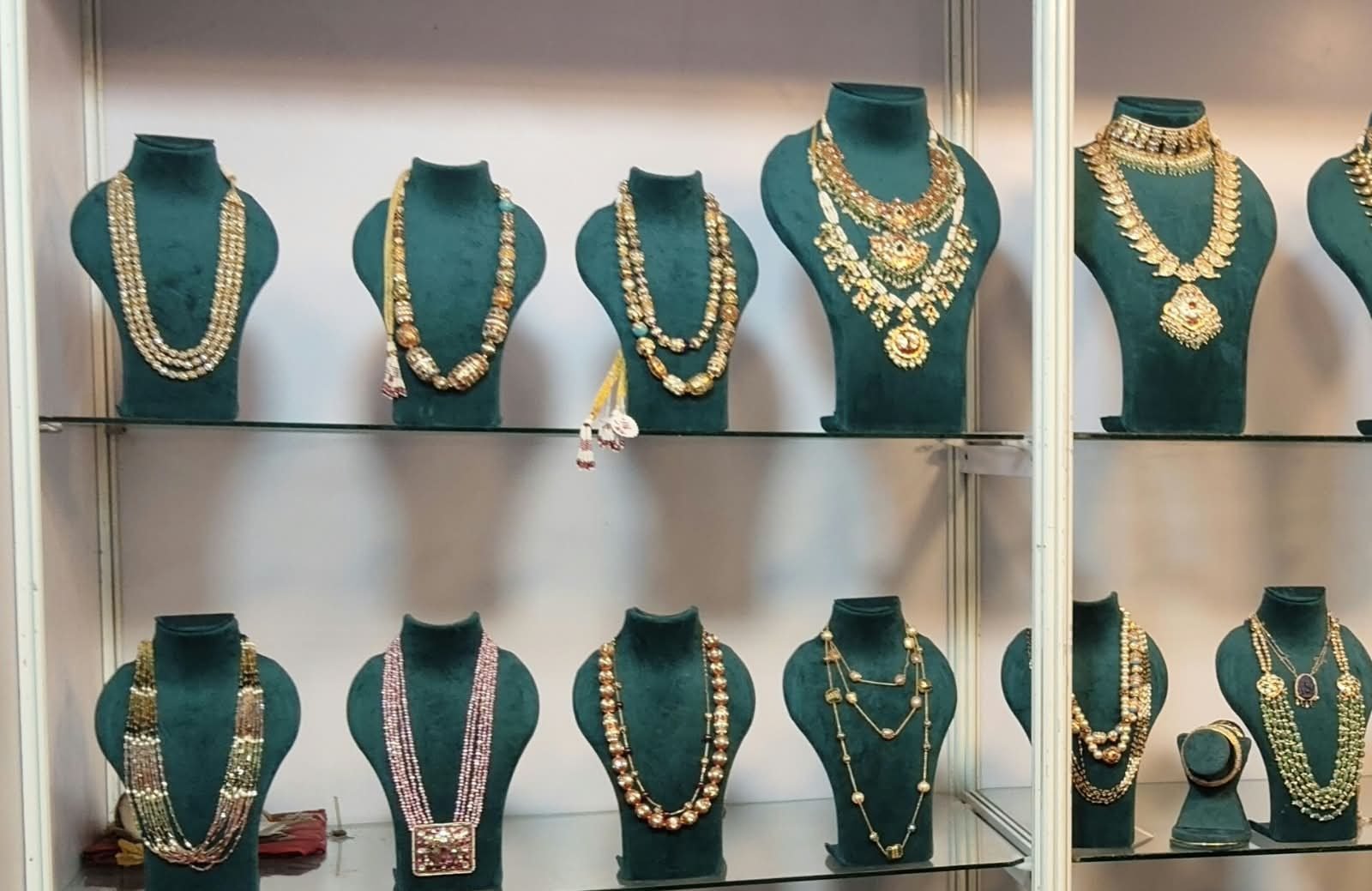 A glass display case of hand-strung gold bead necklaces at the Jewels By Sireesha studio